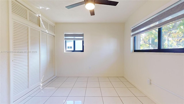 unfurnished bedroom featuring multiple windows, light tile patterned floors, ceiling fan, and a closet