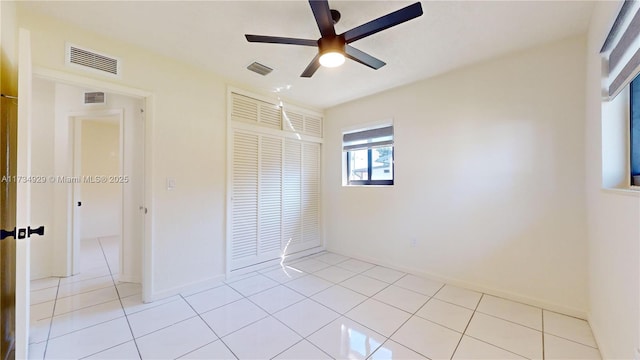 unfurnished bedroom with light tile patterned floors, ceiling fan, and a closet