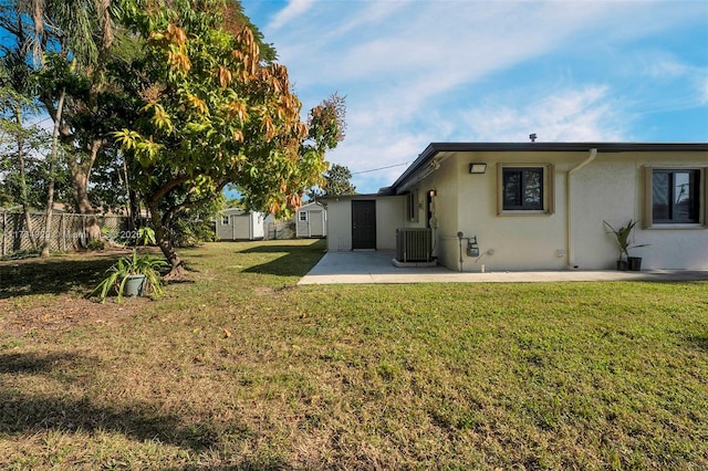 rear view of property with a storage shed, central AC unit, a lawn, and a patio