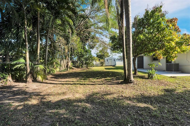 view of yard with cooling unit, a shed, and a patio area