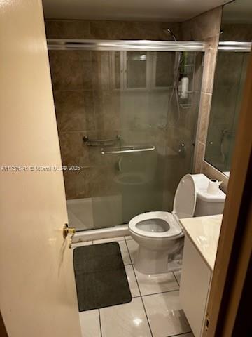 bathroom with tile patterned floors, vanity, toilet, and an enclosed shower