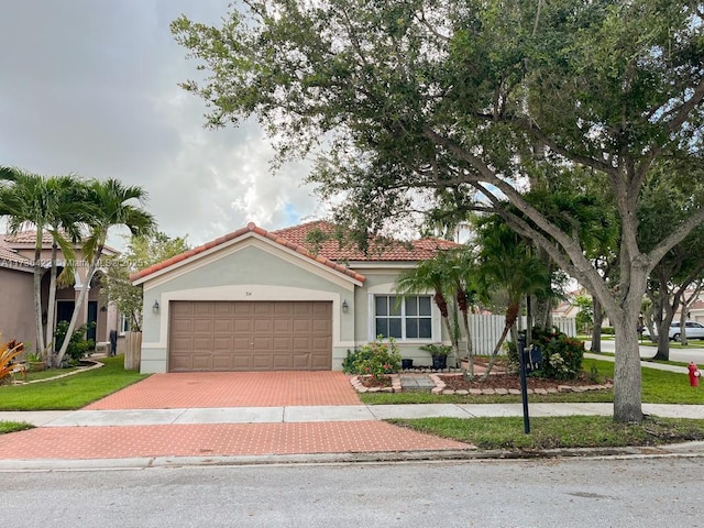 view of front facade featuring an attached garage, a tile roof, decorative driveway, and stucco siding