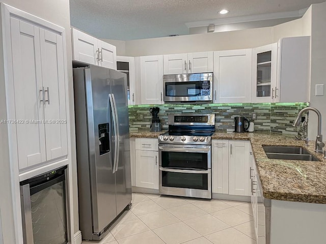 kitchen featuring dark stone countertops, appliances with stainless steel finishes, backsplash, and a sink