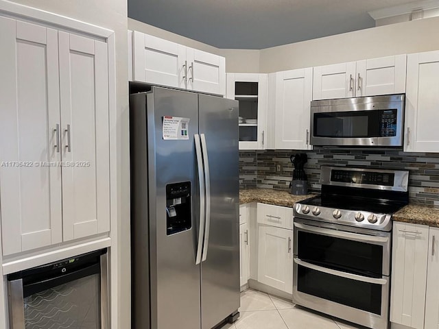 kitchen featuring stainless steel appliances, white cabinets, light tile patterned flooring, and tasteful backsplash