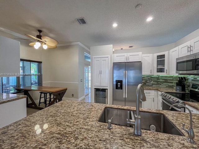 kitchen featuring visible vents, white cabinets, decorative backsplash, appliances with stainless steel finishes, and dark stone countertops