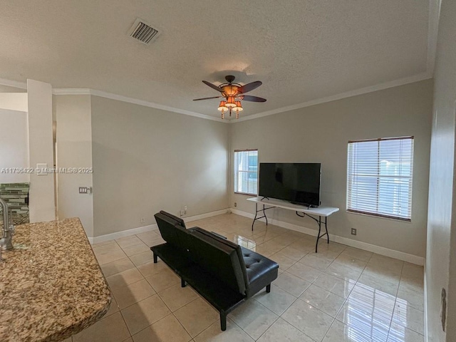 living room with a textured ceiling, light tile patterned floors, visible vents, a ceiling fan, and ornamental molding