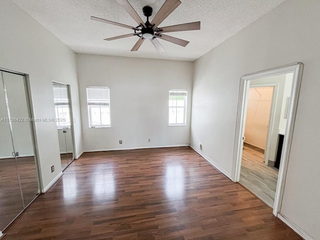 unfurnished bedroom with a textured ceiling, wood finished floors, and baseboards