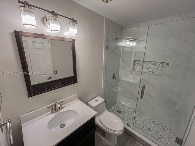 bathroom with vanity, a shower stall, and toilet