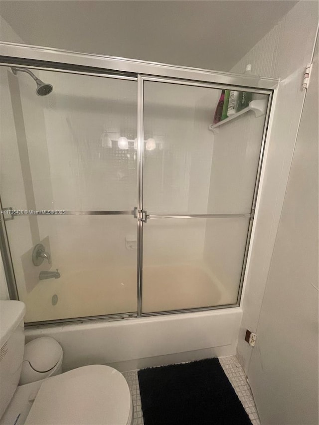 bathroom with toilet and combined bath / shower with glass door