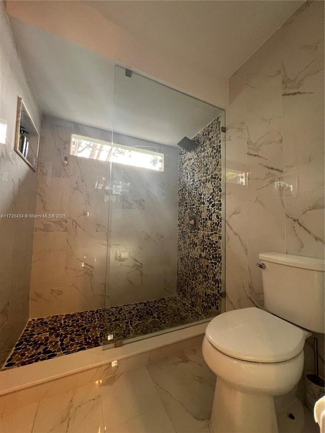 bathroom featuring tiled shower, toilet, and tile walls