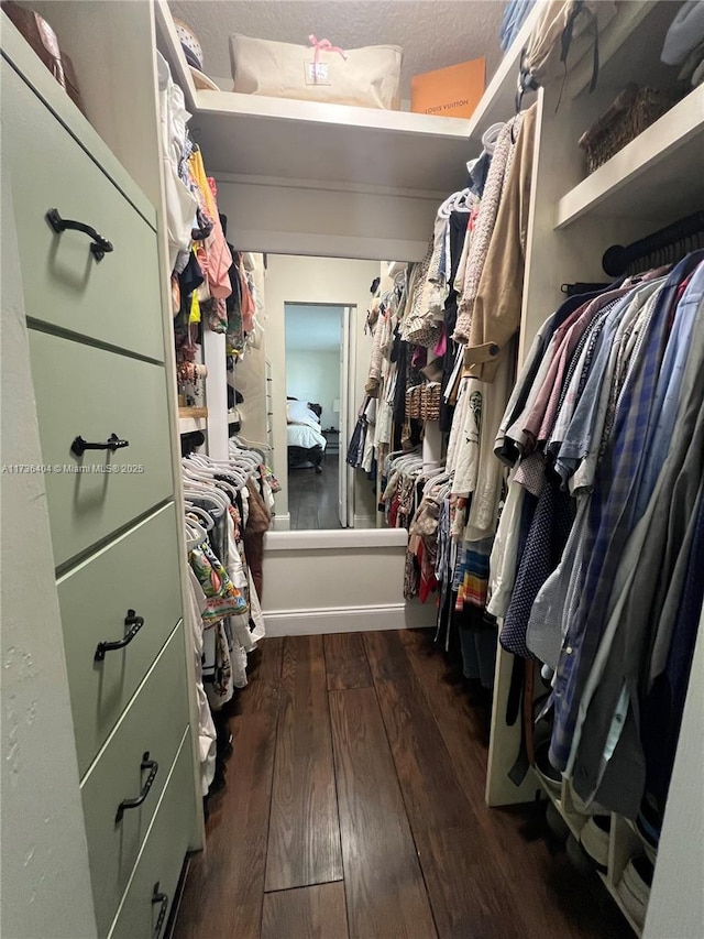 walk in closet with dark wood-type flooring