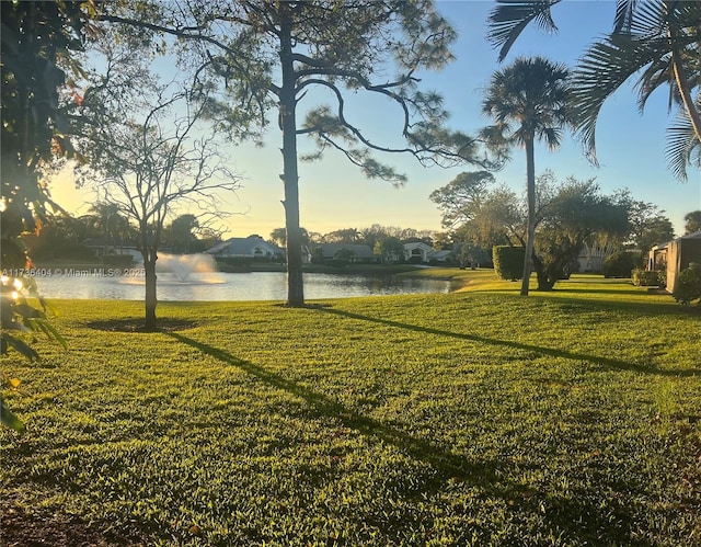 yard at dusk featuring a water view