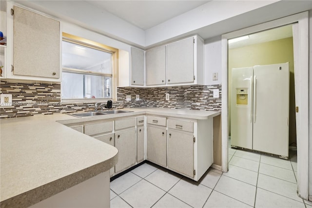 kitchen with white refrigerator with ice dispenser, sink, light tile patterned floors, and backsplash