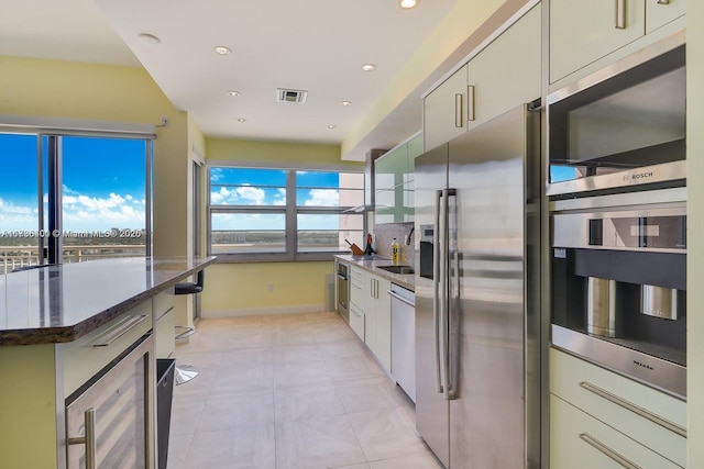 kitchen featuring light tile patterned flooring, wine cooler, a center island, dark stone counters, and stainless steel appliances