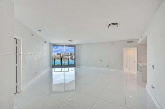 empty room with light tile patterned floors and a wall of windows