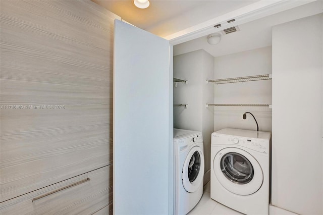 laundry room with light tile patterned floors and washer and clothes dryer