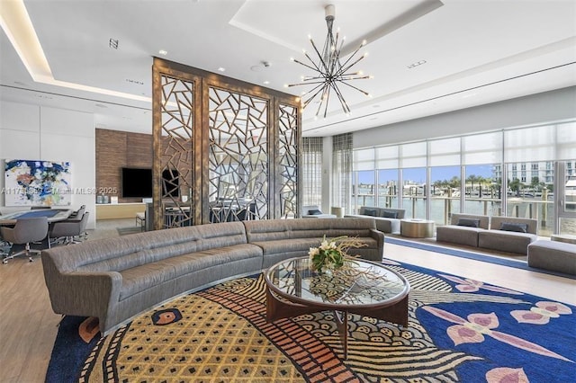 living room featuring a raised ceiling, a high ceiling, hardwood / wood-style floors, and an inviting chandelier