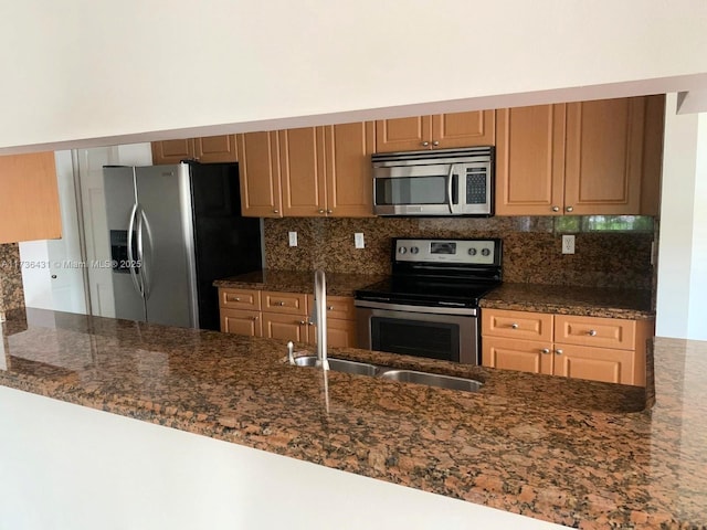 kitchen featuring appliances with stainless steel finishes, dark stone countertops, kitchen peninsula, and decorative backsplash