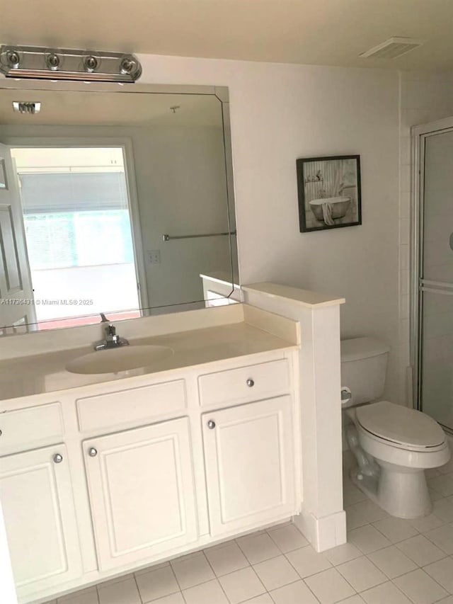 bathroom featuring vanity, tile patterned flooring, a shower with door, and toilet