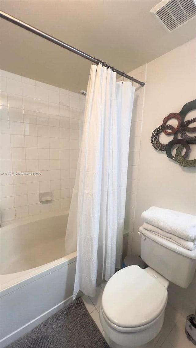 bathroom featuring tile patterned flooring, shower / bath combination with curtain, and toilet