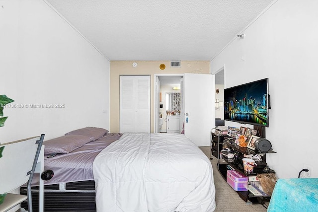 bedroom with ensuite bathroom and a textured ceiling