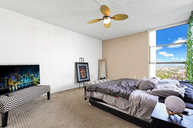 bedroom featuring expansive windows, ceiling fan, carpet, and a textured ceiling