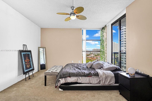 carpeted bedroom with ceiling fan, access to exterior, and a textured ceiling