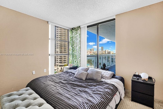 bedroom with expansive windows, light colored carpet, and a textured ceiling