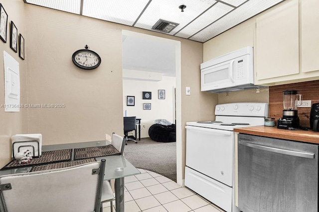 kitchen featuring wooden counters, light tile patterned floors, white cabinets, and white appliances