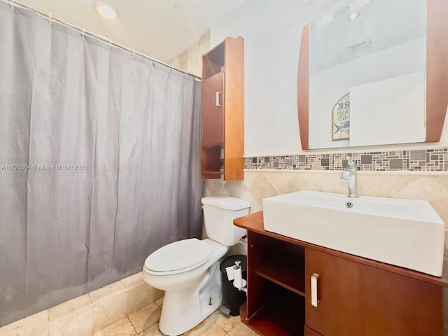 bathroom featuring tile patterned floors, vanity, toilet, and tile walls