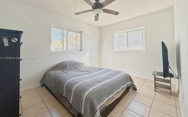 tiled bedroom featuring multiple windows, ceiling fan, and a textured ceiling