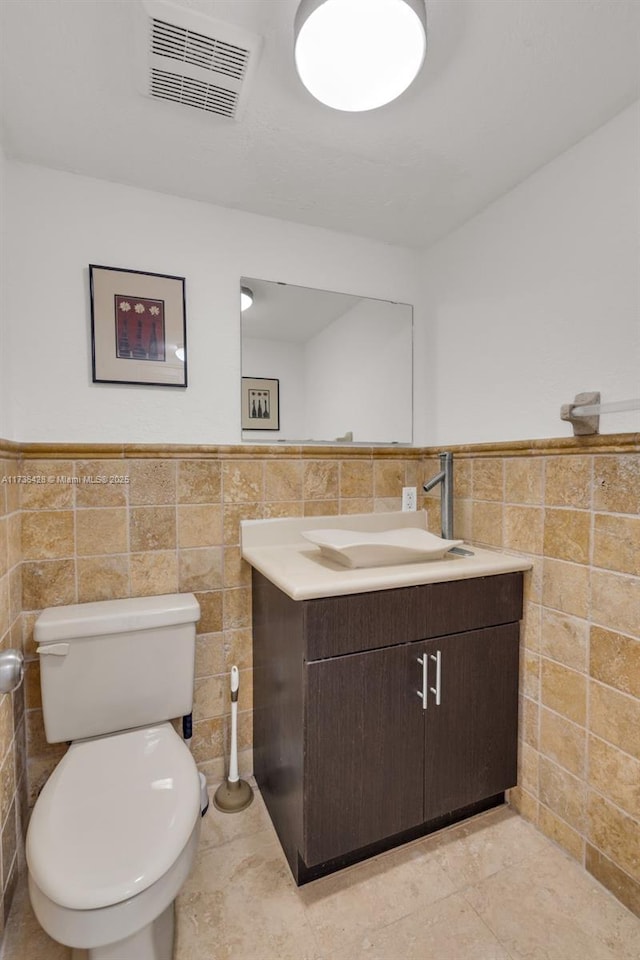 bathroom featuring tile patterned flooring, vanity, tile walls, and toilet