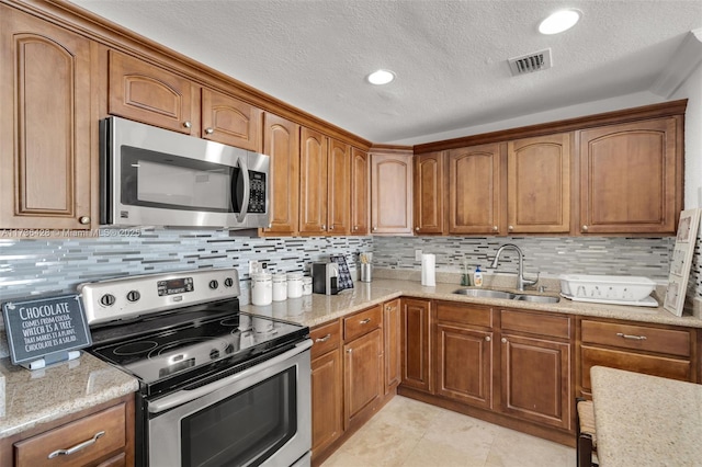 kitchen featuring light tile patterned flooring, sink, light stone counters, tasteful backsplash, and appliances with stainless steel finishes