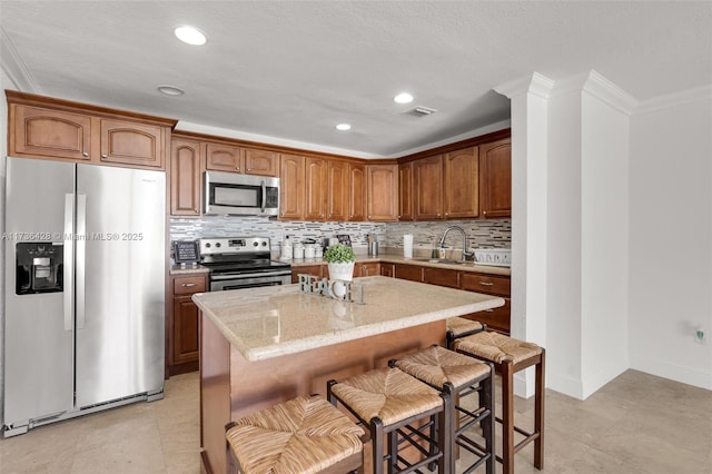 kitchen featuring sink, ornamental molding, a center island, and appliances with stainless steel finishes