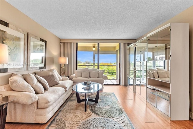 living room with a wall of windows, light hardwood / wood-style floors, and a textured ceiling