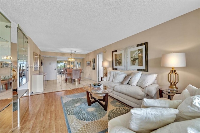 living room with an inviting chandelier, light hardwood / wood-style flooring, and a textured ceiling