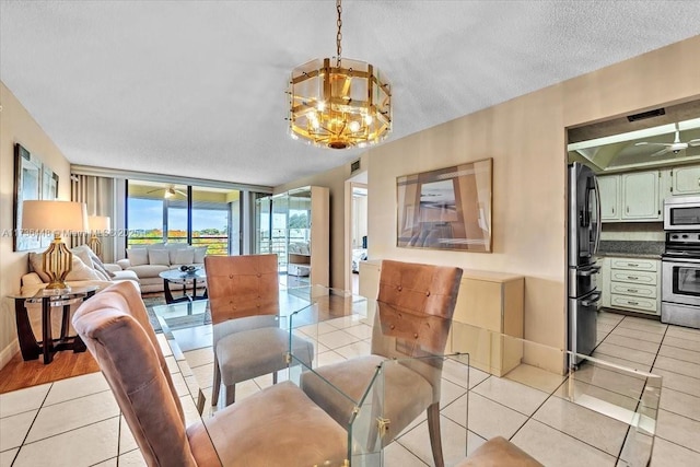 dining area featuring light tile patterned flooring, floor to ceiling windows, ceiling fan with notable chandelier, and a textured ceiling