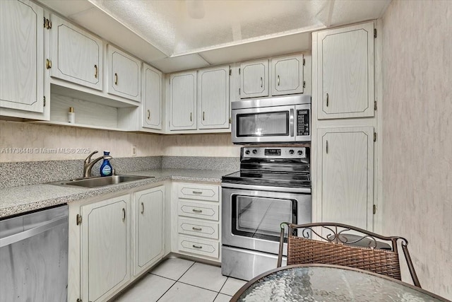 kitchen featuring light tile patterned flooring, white cabinetry, stainless steel appliances, and sink