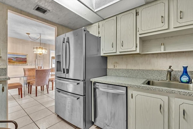 kitchen featuring sink, an inviting chandelier, light tile patterned floors, appliances with stainless steel finishes, and pendant lighting