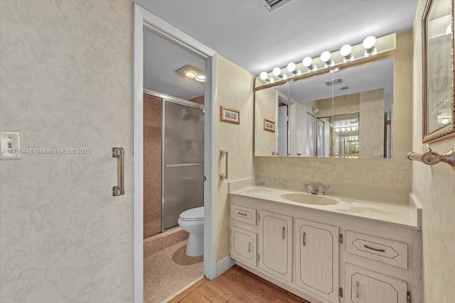 bathroom featuring hardwood / wood-style flooring, vanity, toilet, and walk in shower