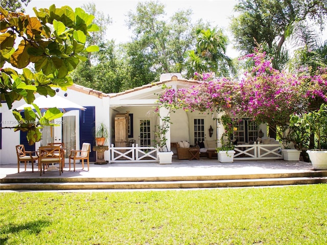 rear view of house featuring a patio area, stucco siding, and a yard