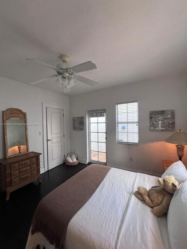 bedroom featuring multiple windows, ceiling fan, access to outside, and a textured ceiling