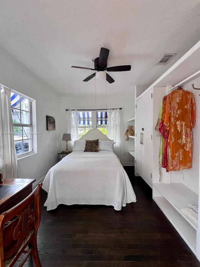 bedroom with multiple windows, dark hardwood / wood-style floors, and a textured ceiling