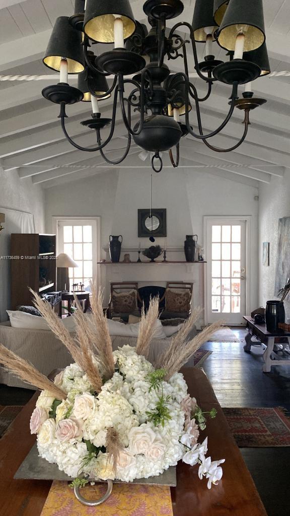 living room with lofted ceiling with beams, plenty of natural light, hardwood / wood-style floors, and a notable chandelier