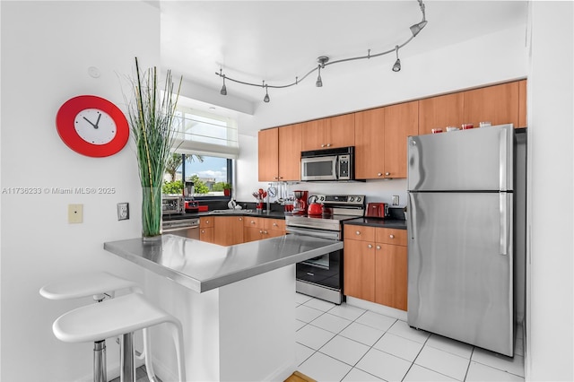 kitchen with light tile patterned flooring, rail lighting, sink, kitchen peninsula, and stainless steel appliances