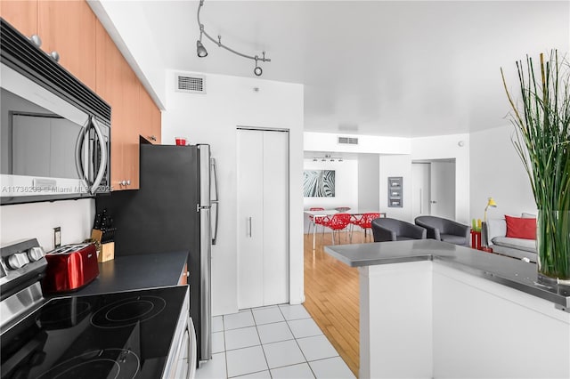 kitchen featuring track lighting, light hardwood / wood-style floors, and appliances with stainless steel finishes