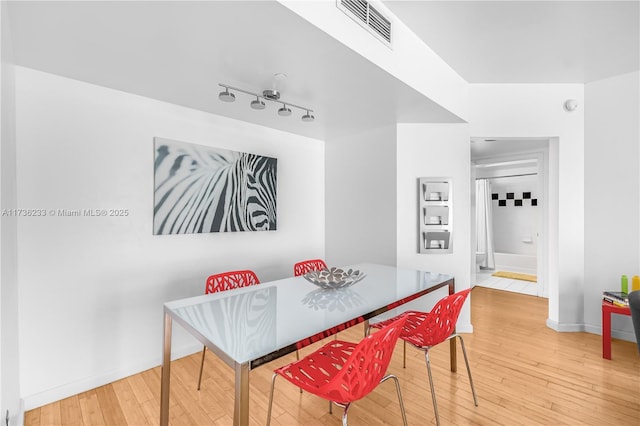 dining room with hardwood / wood-style flooring and rail lighting