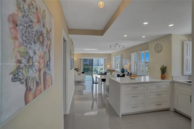 kitchen featuring white cabinetry, kitchen peninsula, and light tile patterned flooring