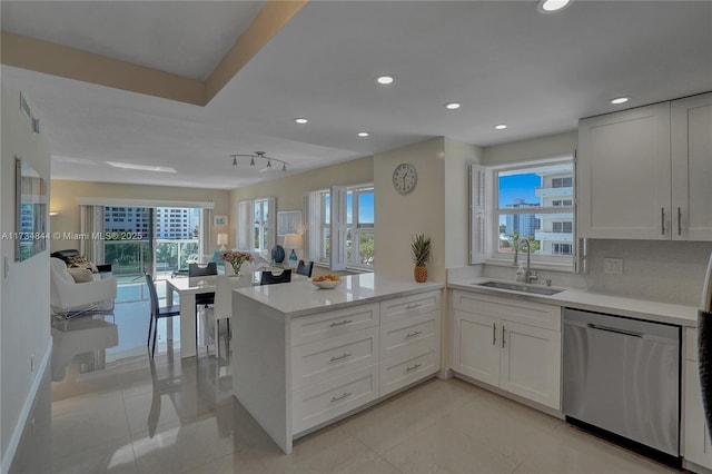 kitchen with sink, dishwasher, a healthy amount of sunlight, white cabinets, and kitchen peninsula