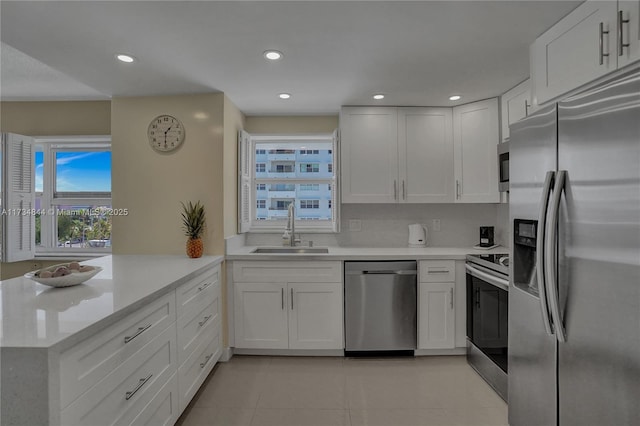 kitchen with stainless steel appliances, white cabinetry, sink, and kitchen peninsula